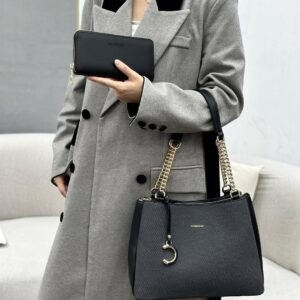 A stylish black handbag with gold chain accents rests on a cream fabric, accompanied by a matching black wallet.
