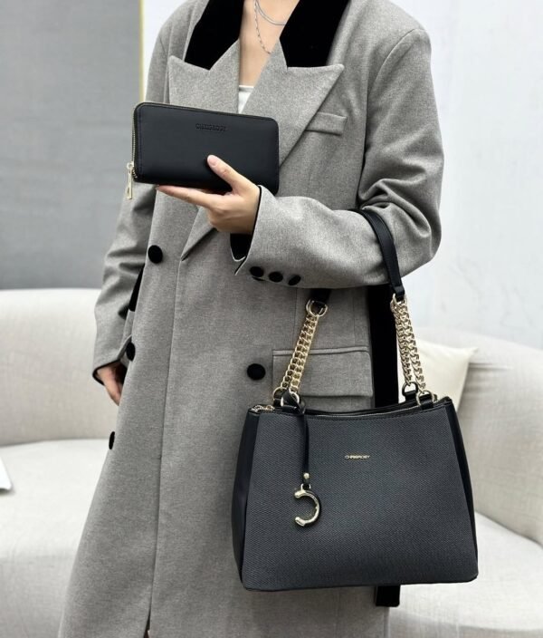 A stylish black handbag with gold chain accents rests on a cream fabric, accompanied by a matching black wallet.